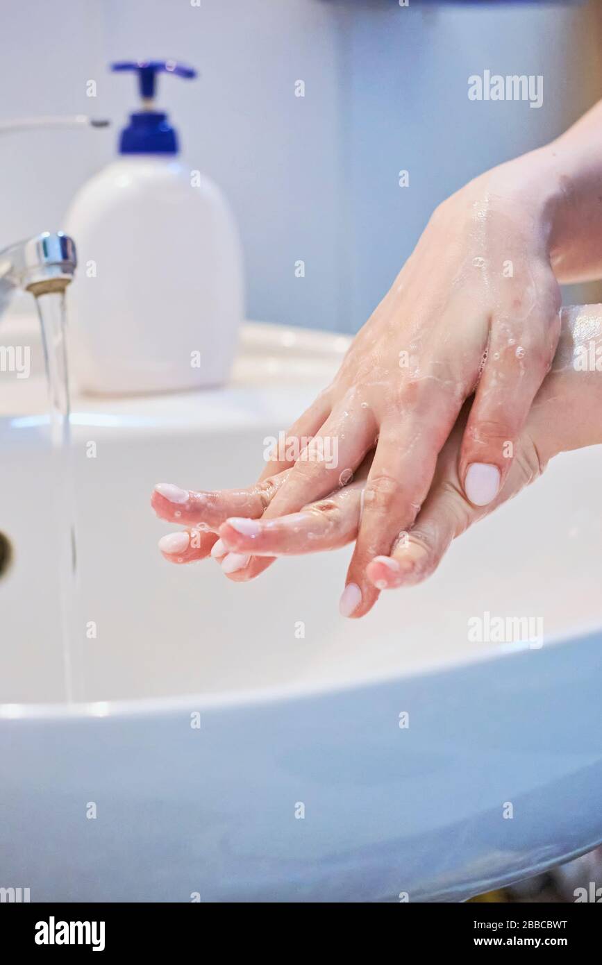 Close-up view of woman using soap and washing hands under the water tap ...