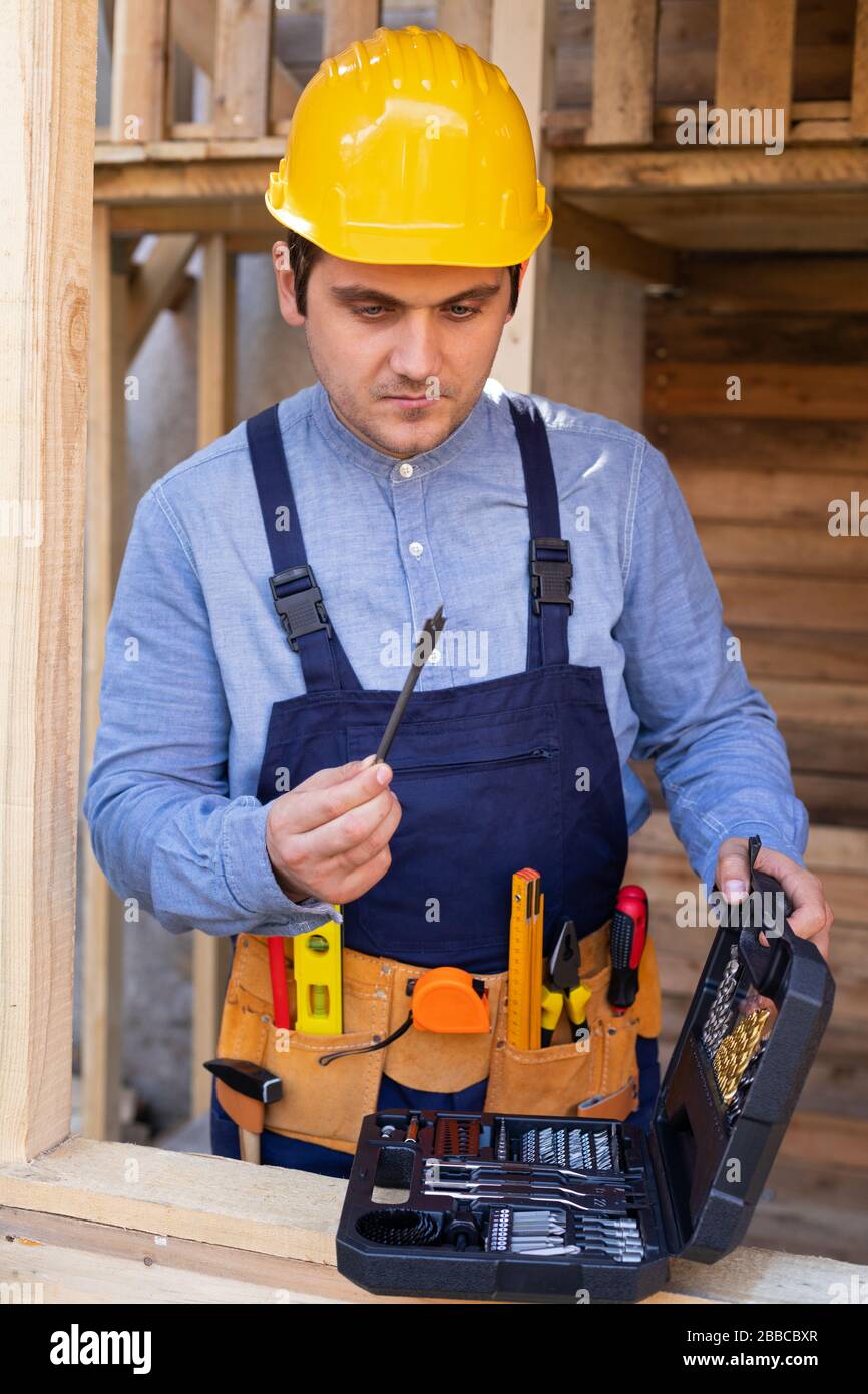 Portrait of a confident young workman wearing yellow helmet, blue ...