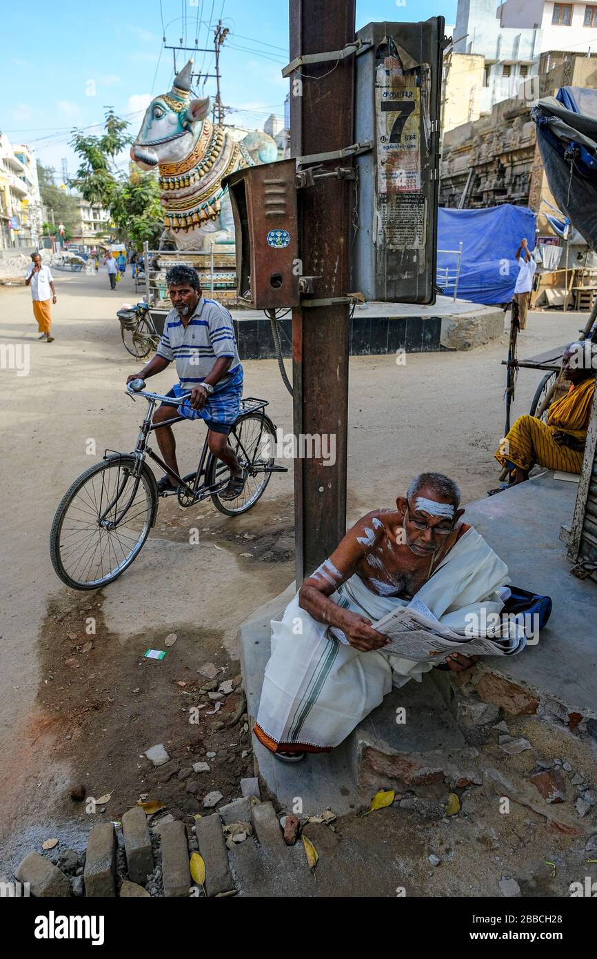 Madurai, India - March 2020: A man reading the newspaper next to the blue Nandi in front of the entrance to the Pudhu Mandapa on March 10, 2020 in Mad Stock Photo