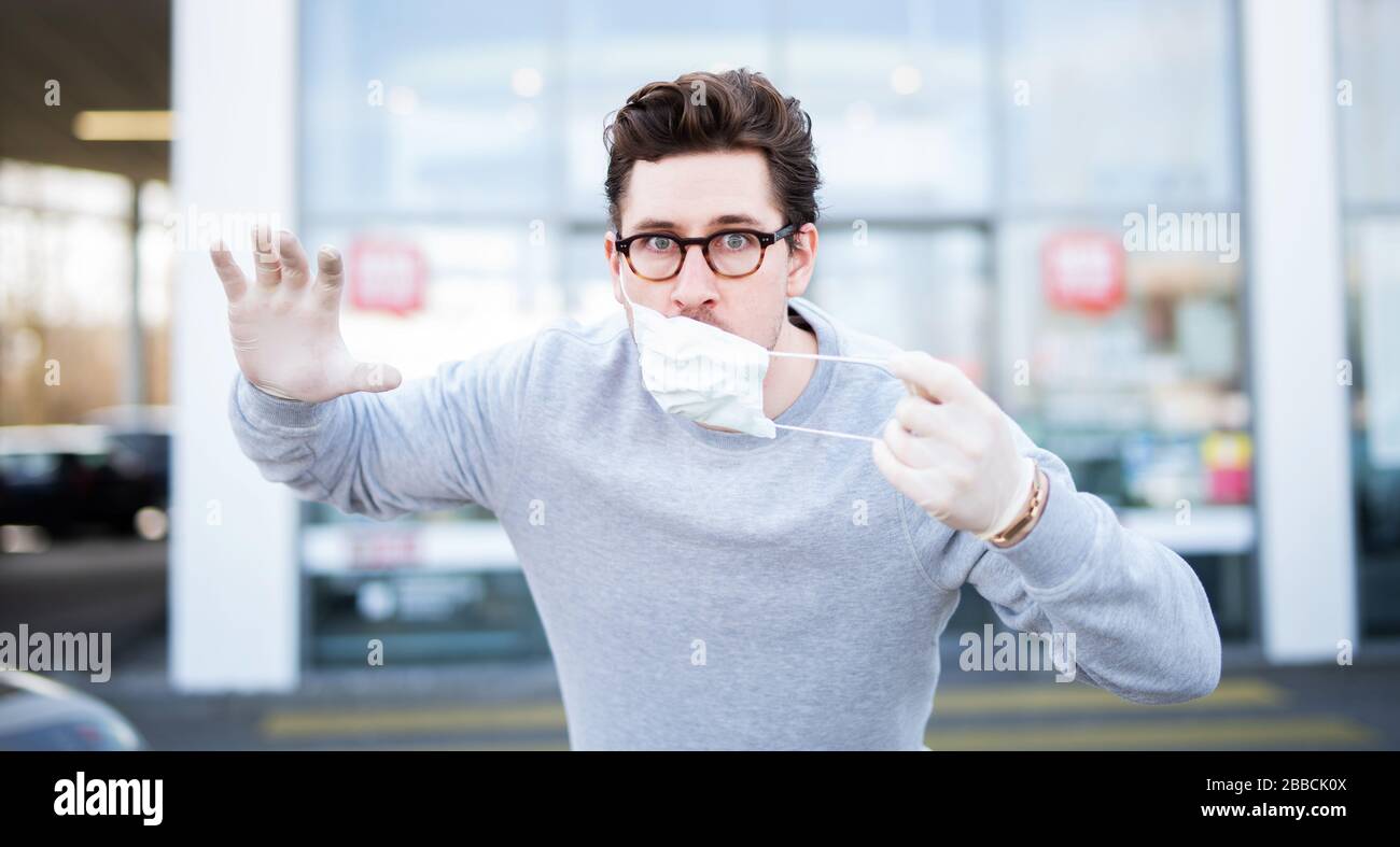 A man panicking while shopping, worried about getting the corona virus. He is wearing a breathing mask and rubber gloves. Stock Photo