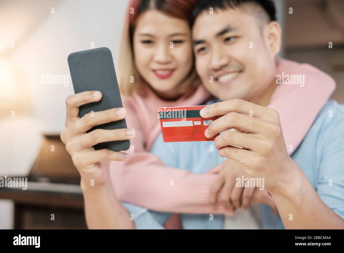 Asian couple use mobile phone shopping online with credit card together in living room at home.couple in home concept Stock Photo
