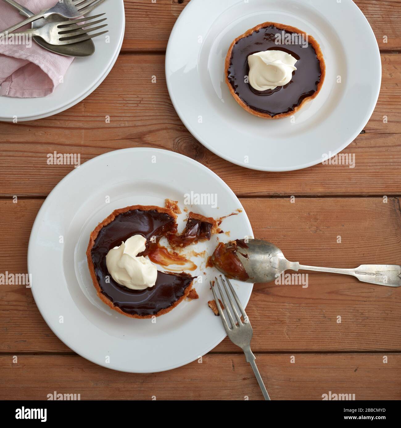 Caramel tarts overhead two plates white cutlery gloss shine pastry Stock Photo