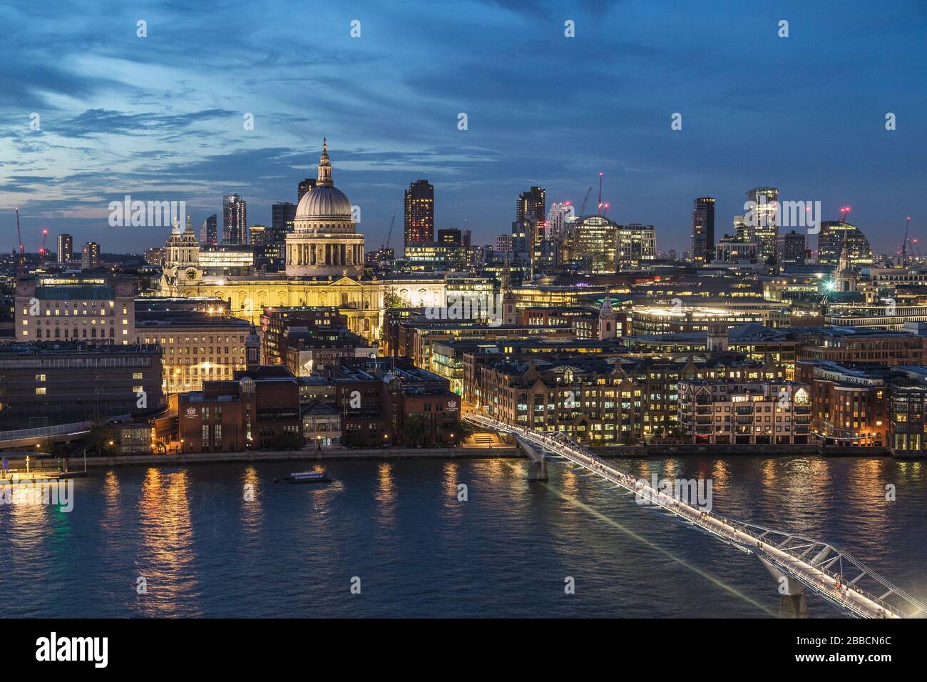 LONDON, UK - 24TH AUGUST 2019: A view towards St Pauls from across the River Thames at night. People can be seen on Millennium Bridge Stock Photo