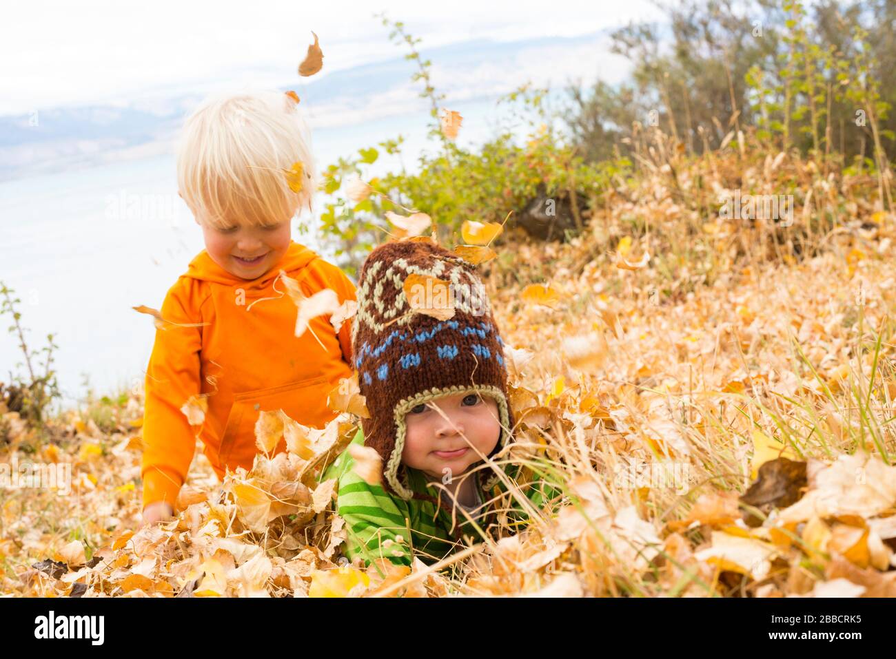 Two boys playing in the leaves on the shore of Lago General Carrera, Chile Stock Photo
