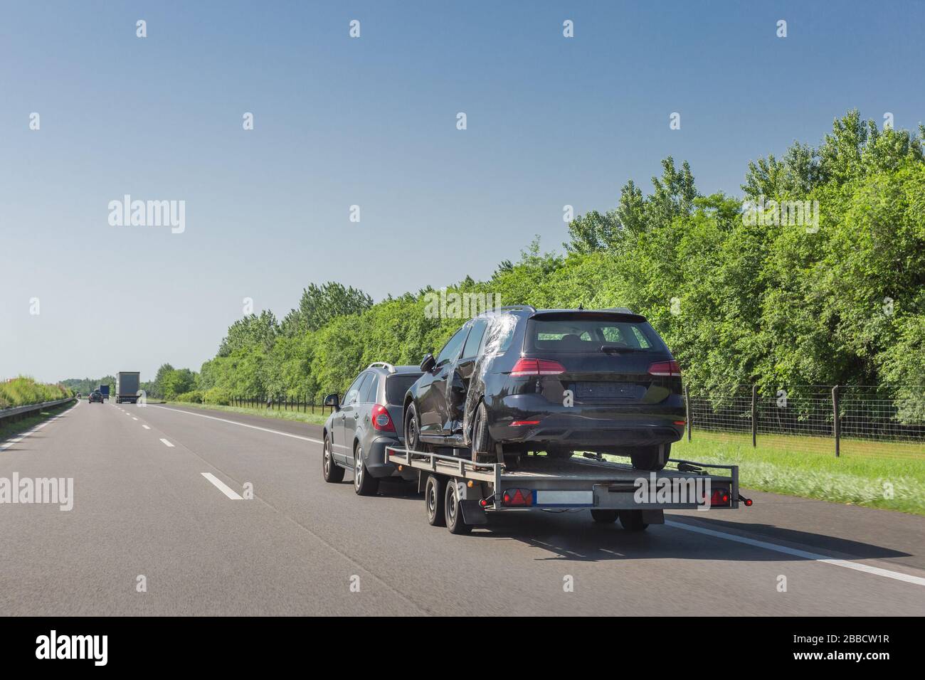 Black broken car after accident on tow truck. Car transported on car