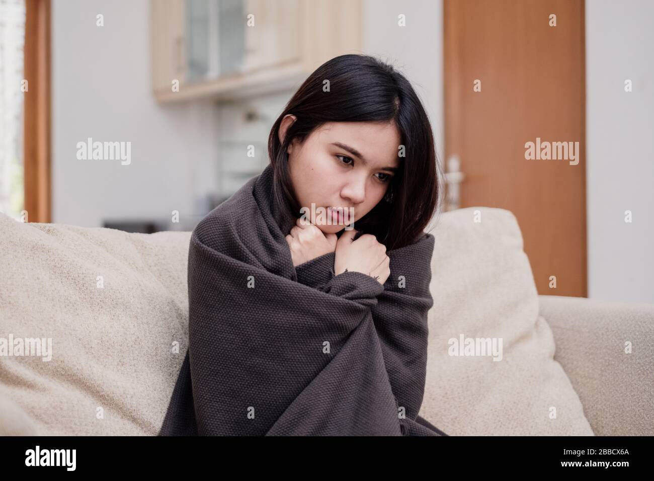 Portrait of a shivering and sick flu young woman asian at home. Pandemic 2019 Coronavirus 2019-nCoV Concept. Stock Photo