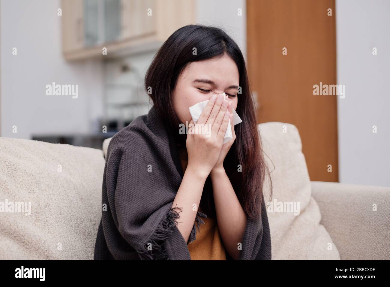 Portrait of a sneezing and sick flu young woman asian at home. Pandemic 2019 Coronavirus 2019-nCoV Concept. Stock Photo