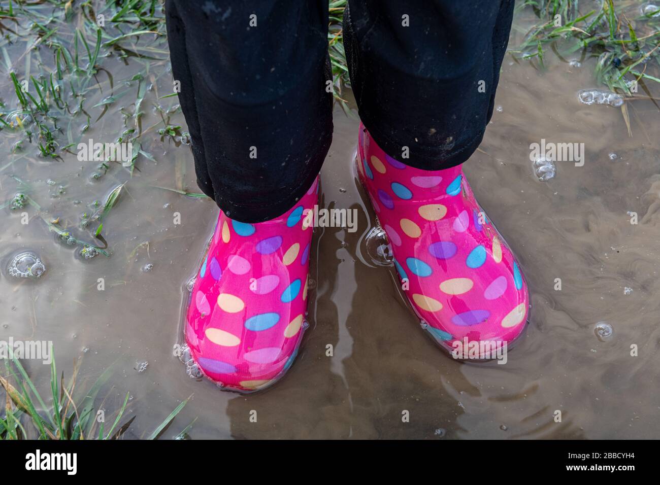 child walking in mud with multicolored boots Stock Photo - Alamy