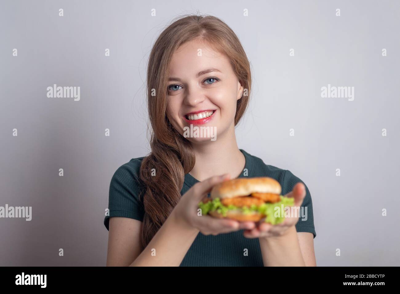 Smiling young Caucasian woman girl holding eating chicken burger Stock