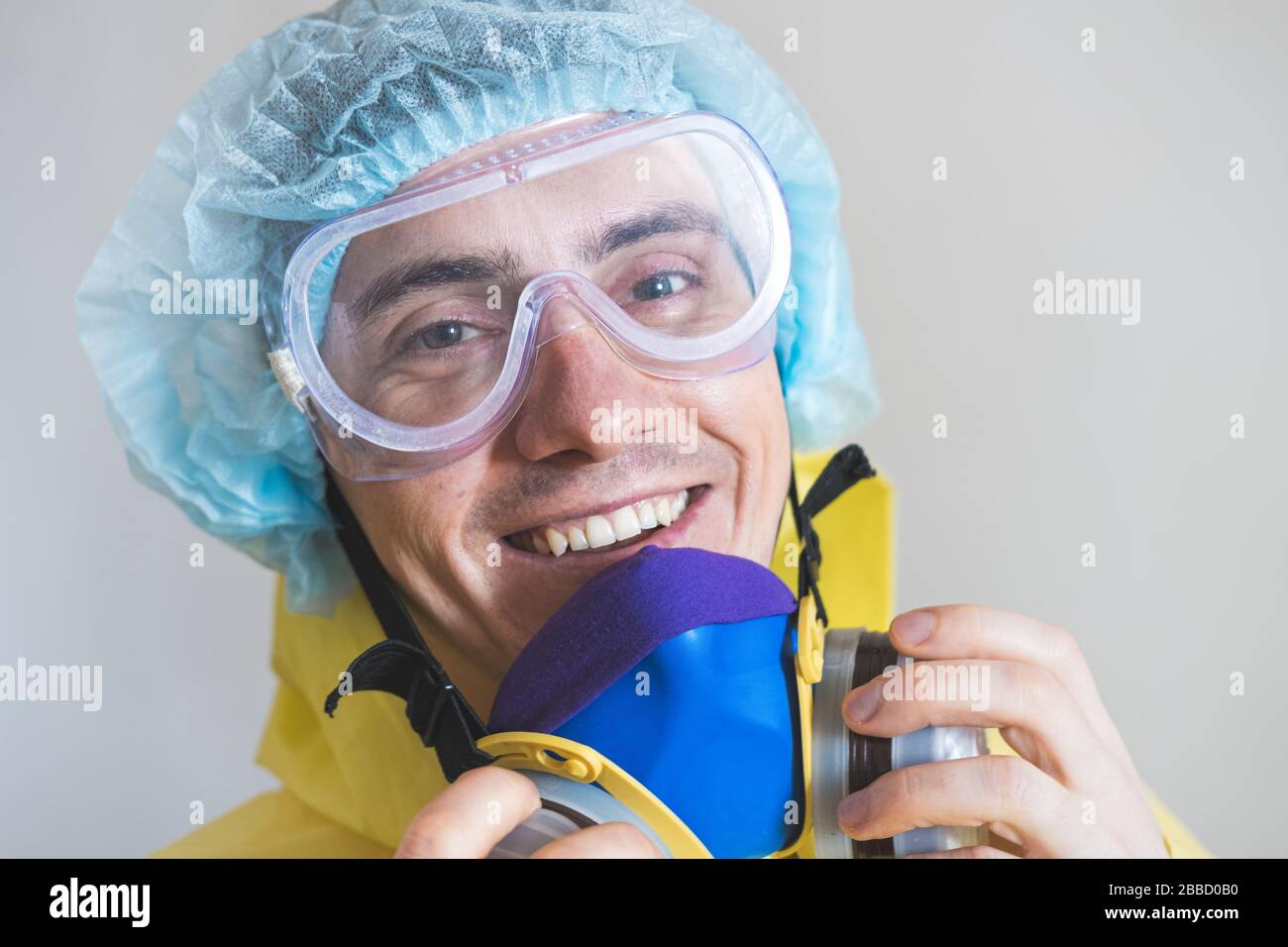 Portrait of a happy medical worker puts off protective gear after a shift. Concept of covid-19 epidemic, healthcare personell and overworking Stock Photo