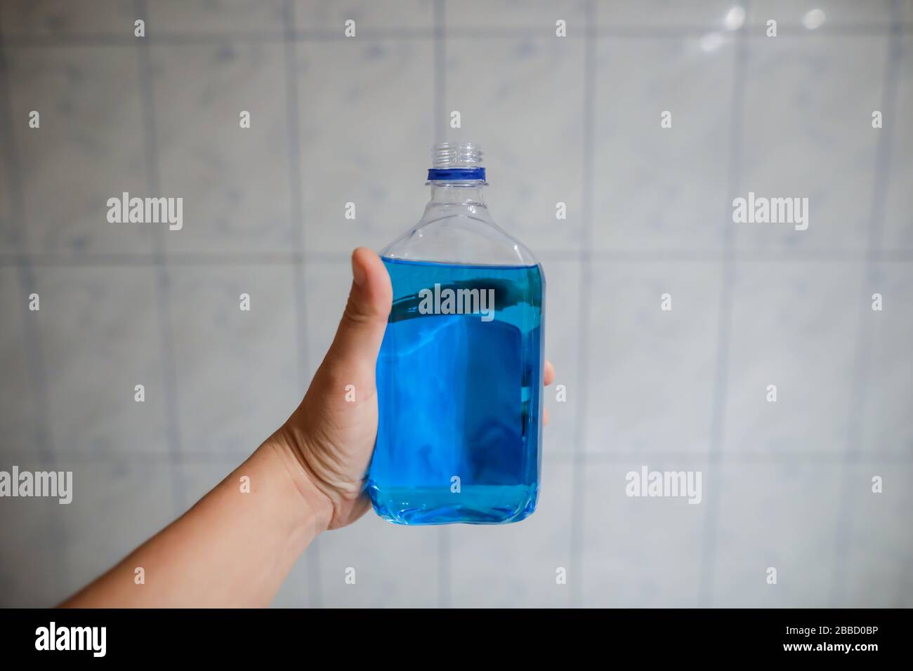 Shallow depth of field image (selective focus) with the hand of a man holding a plastic bottle of spirt - Romanian medical alcohol used for disinfecti Stock Photo