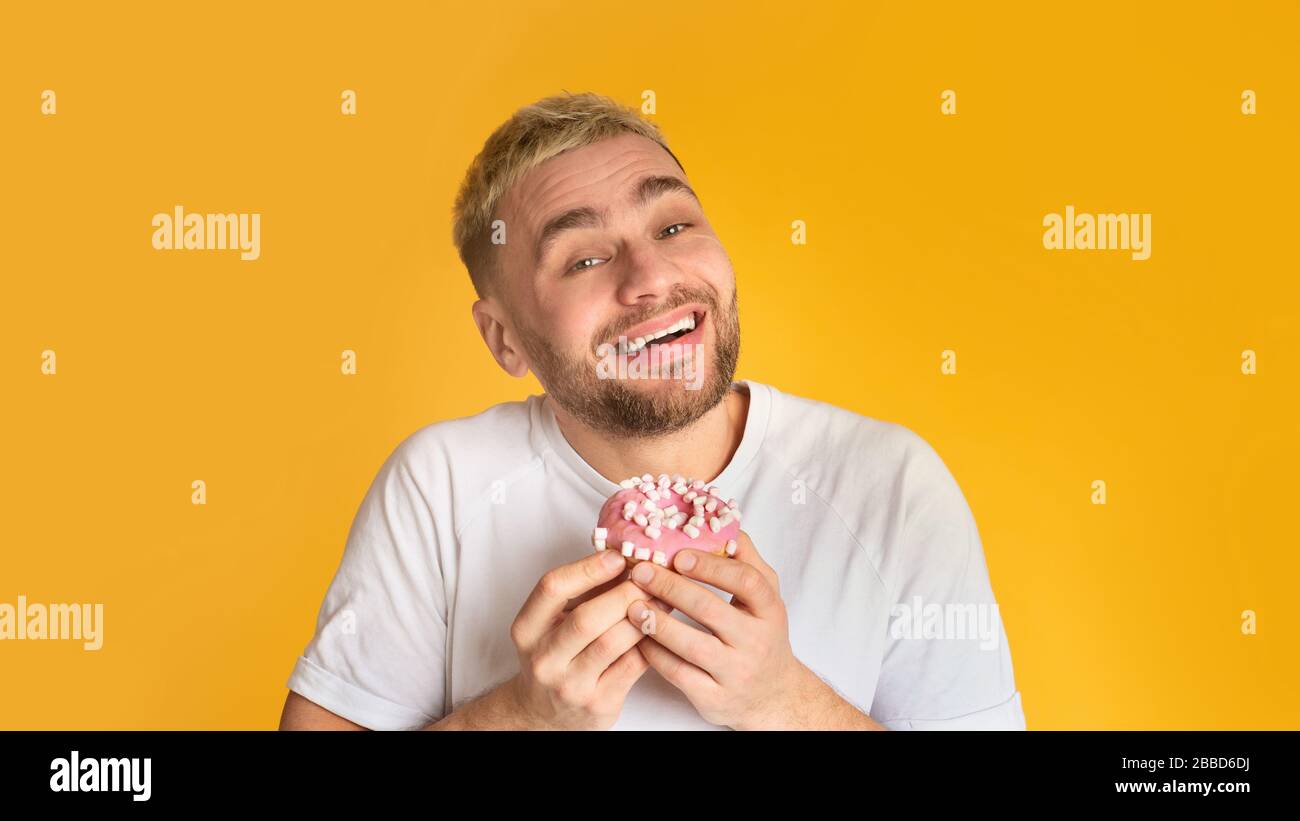 Sweet tooth man happy eat donut, panorama Stock Photo