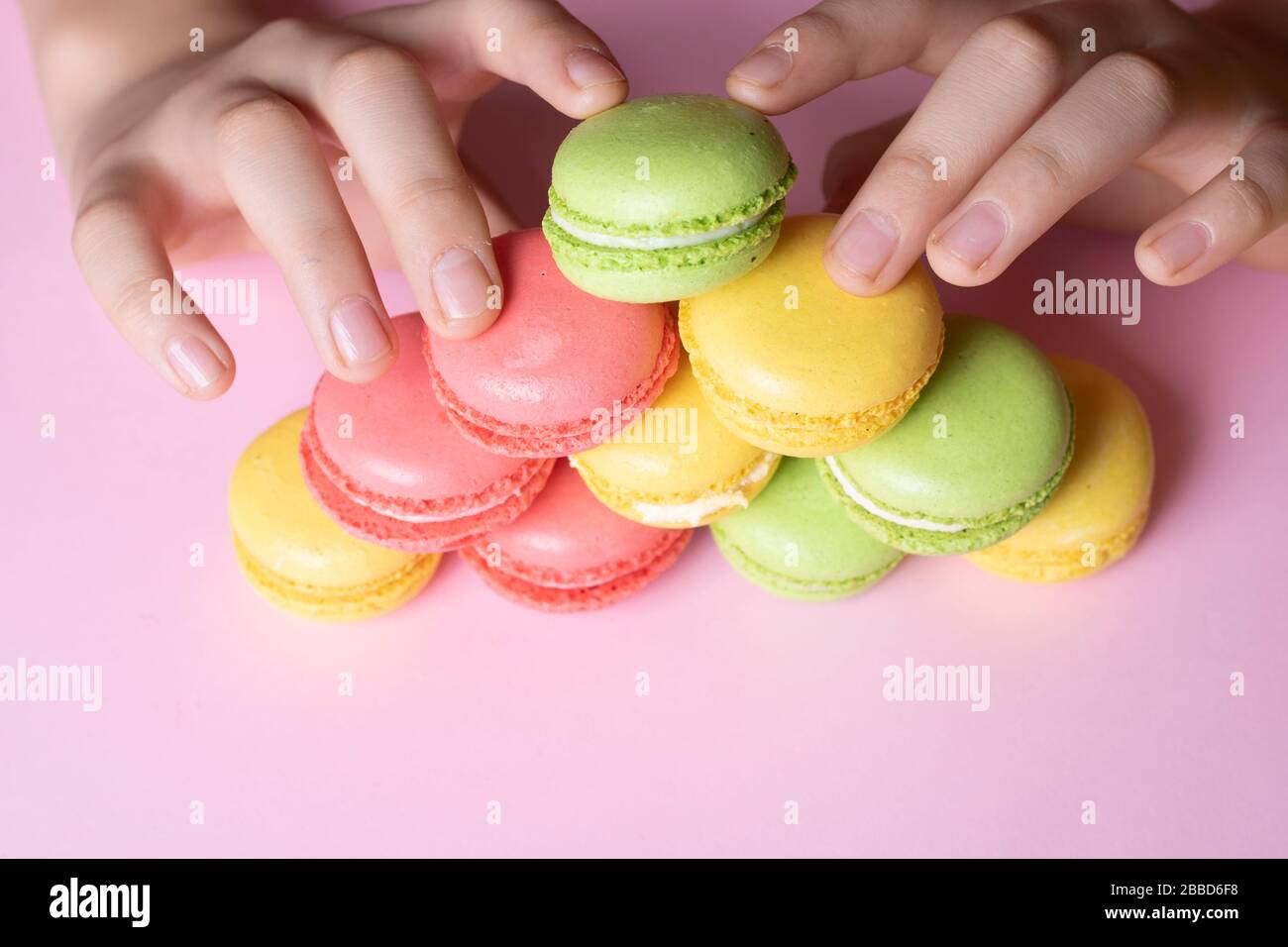 Boy holding colorful French macarons in hands, pyramid concept Stock Photo