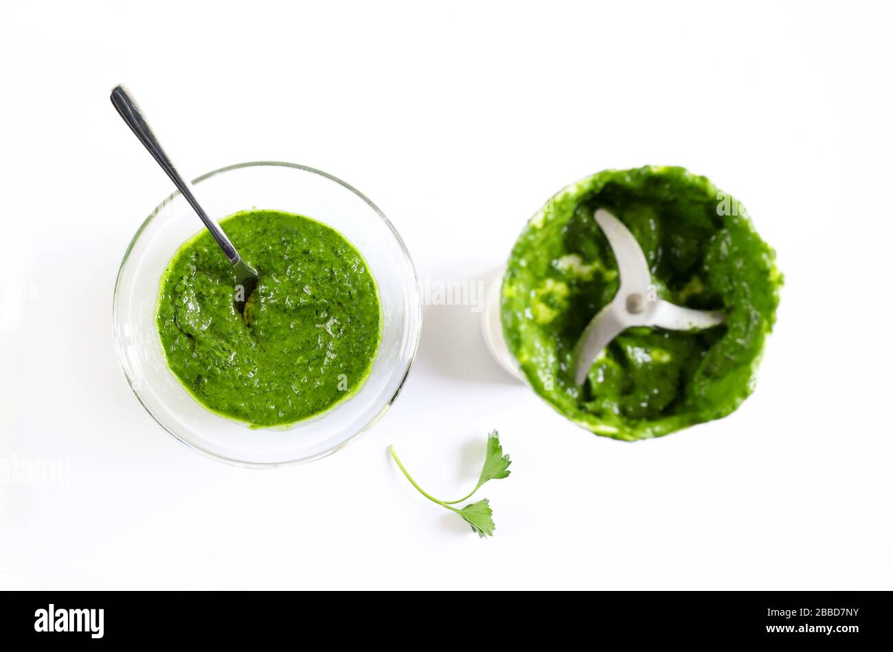 Closeup of a bowl with parsley sauce and a hand blender immersed in the