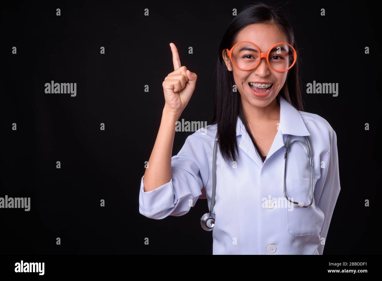 Happy young Asian woman doctor with eyeglasses pointing up Stock Photo ...