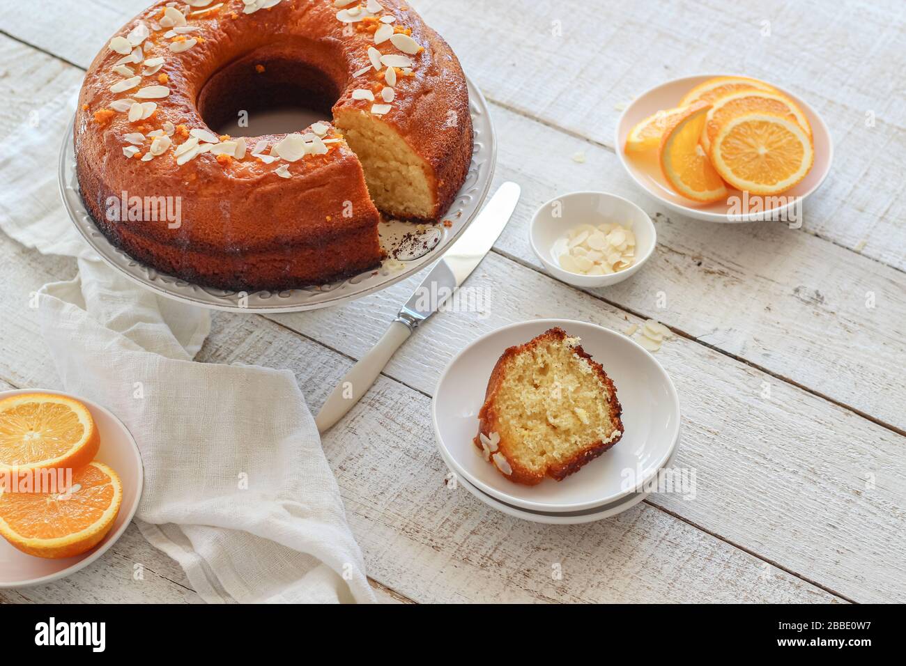 Sliced orange cake served on a white wooden table Stock Photo