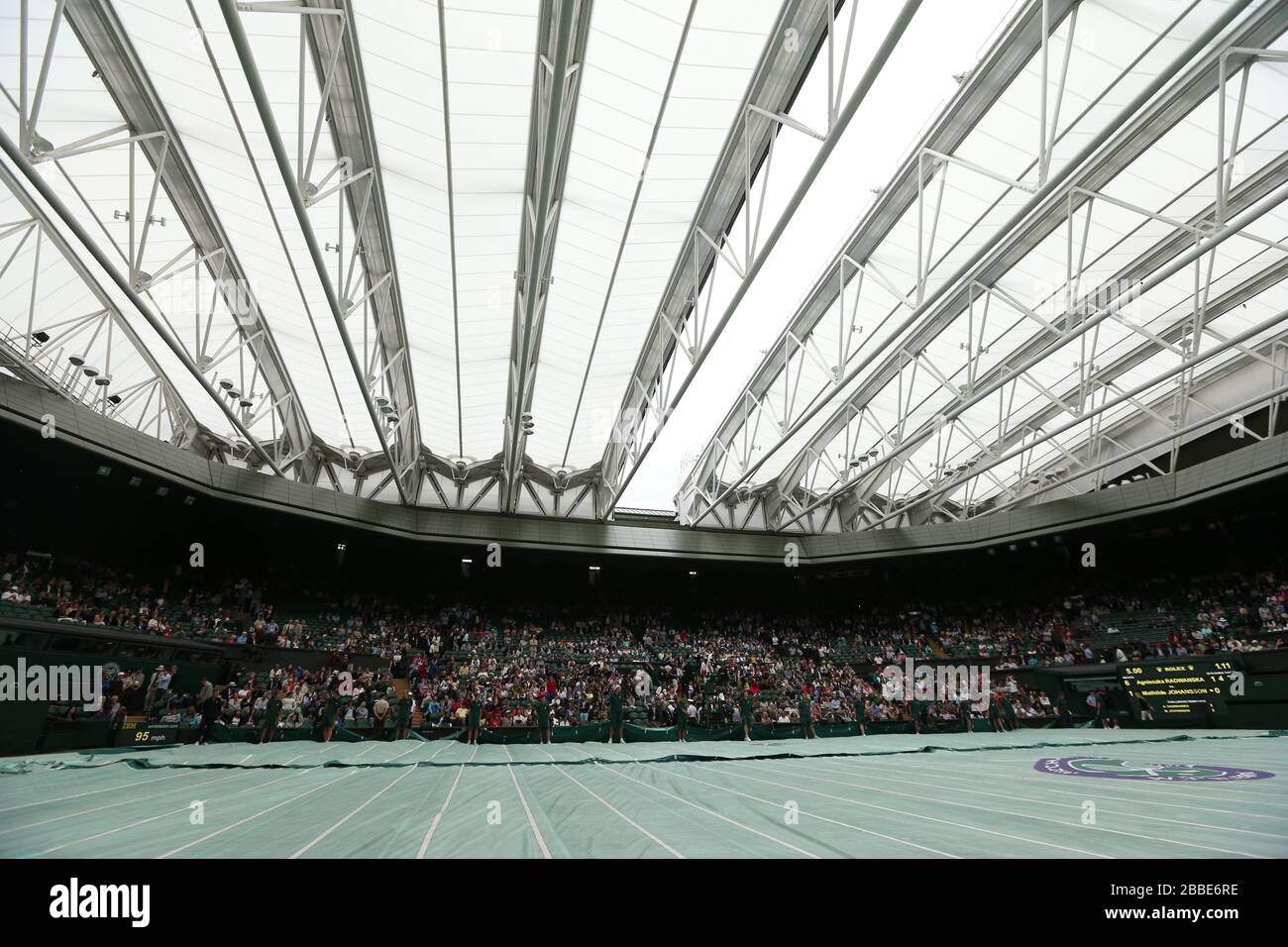 Groundstaff race to put the covers on centre court as rain stops play during the match between Poland's Agnieszka Radwanska and France's Mathilde Johansson during day four of the Wimbledon Championships at The All England Lawn Tennis and Croquet Club, Wimbledon. Stock Photo