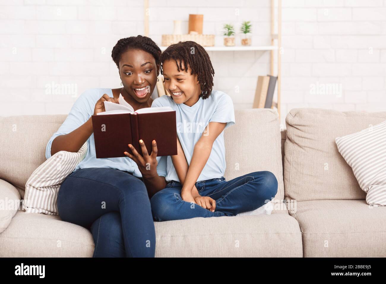 Happy afro family reading book in living room Stock Photo