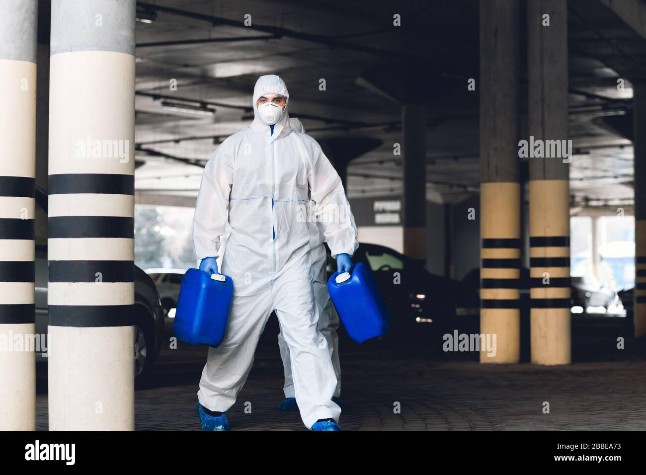 Worker in protective suit making wet disinfection of streets Stock Photo