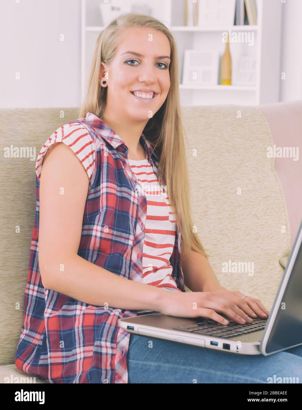 Beautiful young woman lying on the couch with laptop computer at home ...