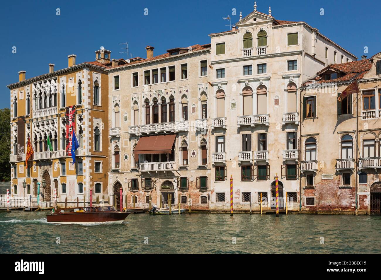 Water taxi on Grand Canal and moored boats in front of Renaissance architectural style palace buildings including the Palazzo Cavalli-Franchetti palace, San Marco, Venice, Veneto, Italy Stock Photo