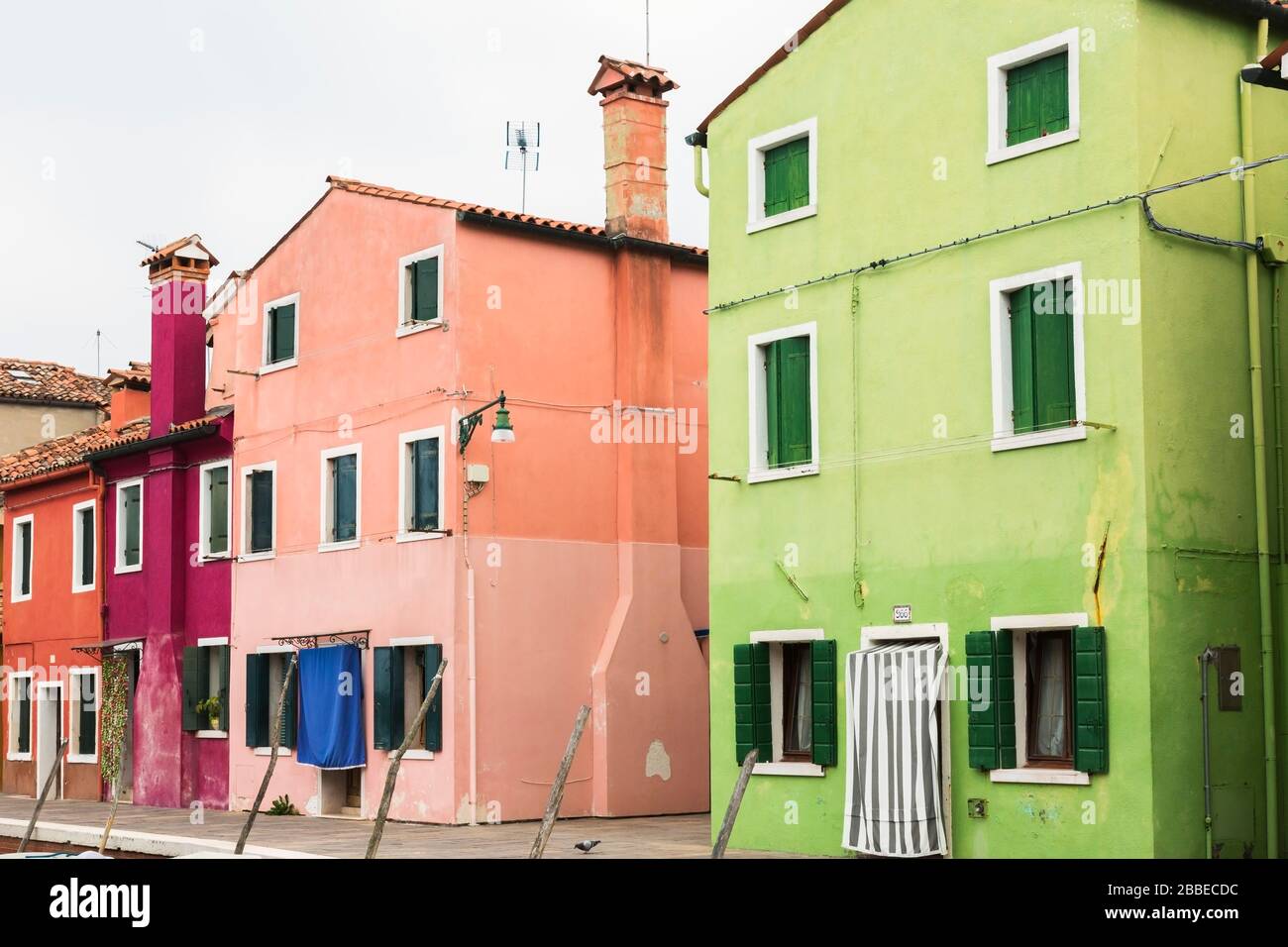 Green, pink, purple and red stucco houses decorated with curtains over entrance doors, Burano Island, Venetian Lagoon, Venice, Veneto, Italy Stock Photo
