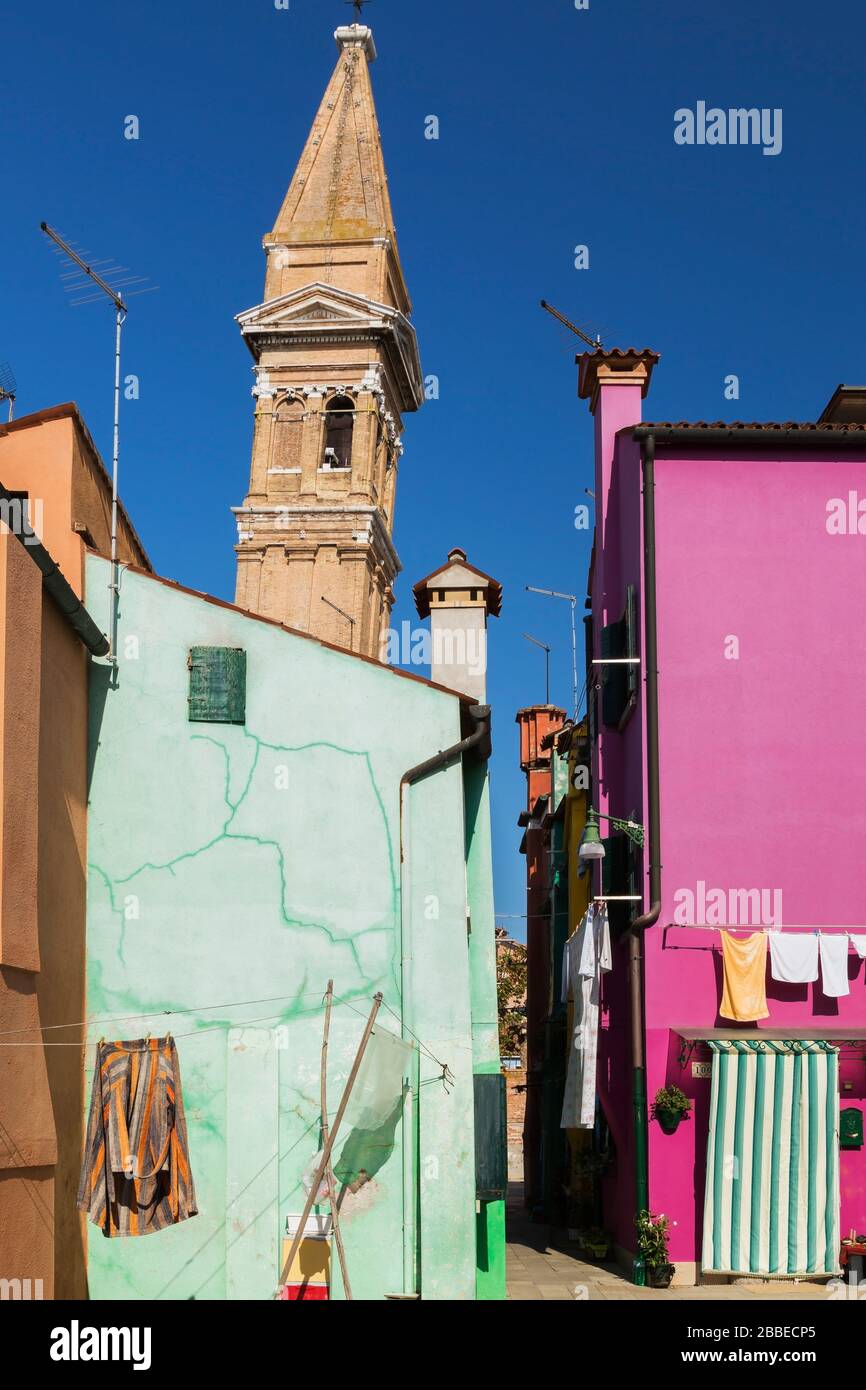 Green and purple stucco houses with alleyway and leaning bell tower of San Martino church, Burano Island, Venetian Lagoon, Venice, Veneto, Italy Stock Photo