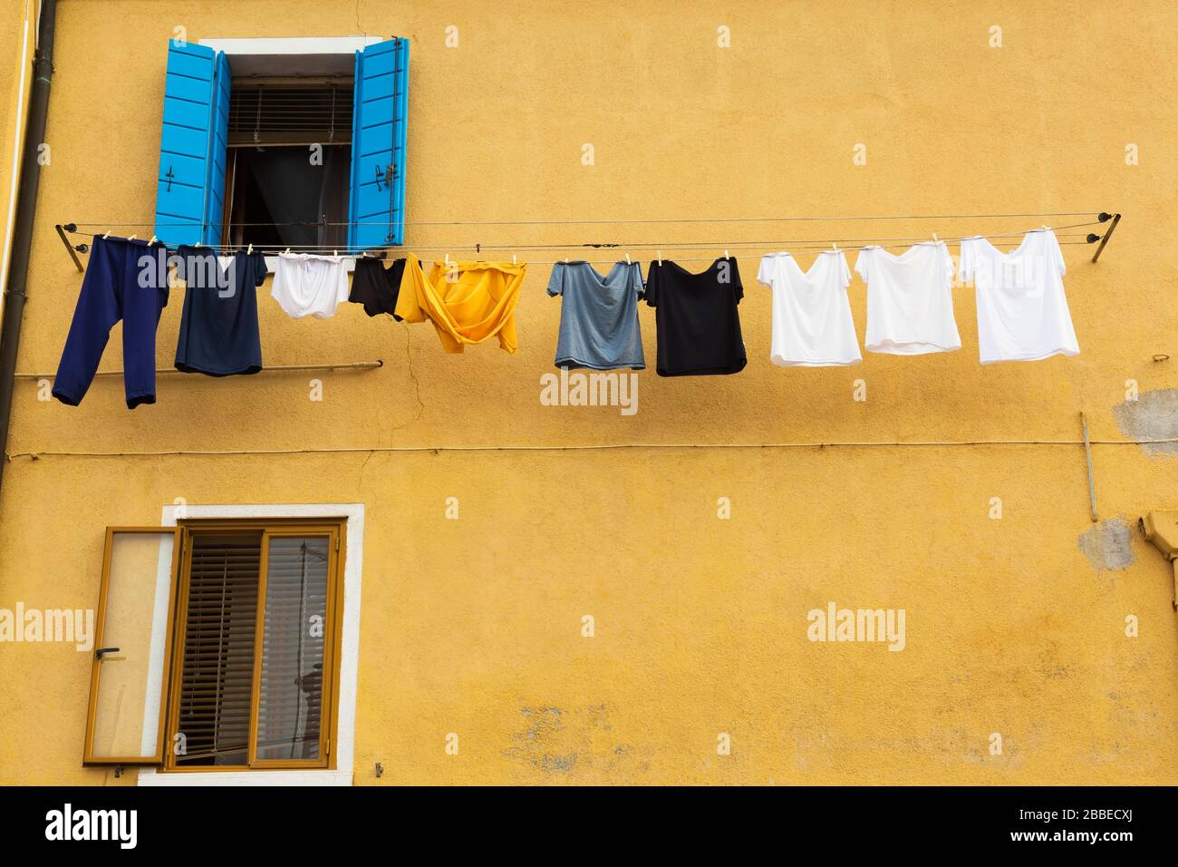 Yellow stucco house facade with washed clothes on clothesline, Burano Island, Venetian Lagoon, Venice, Veneto, Italy Stock Photo