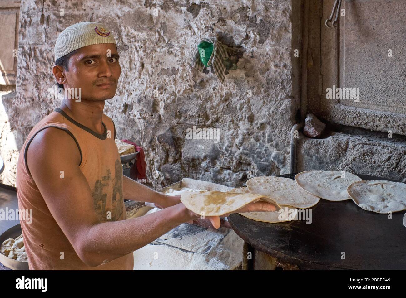 In a hole-in-the-wall eatery in Mumbai, India, a cook is preparing chapatis (unleavened flat breads) on a tawa (hot plate) Stock Photo