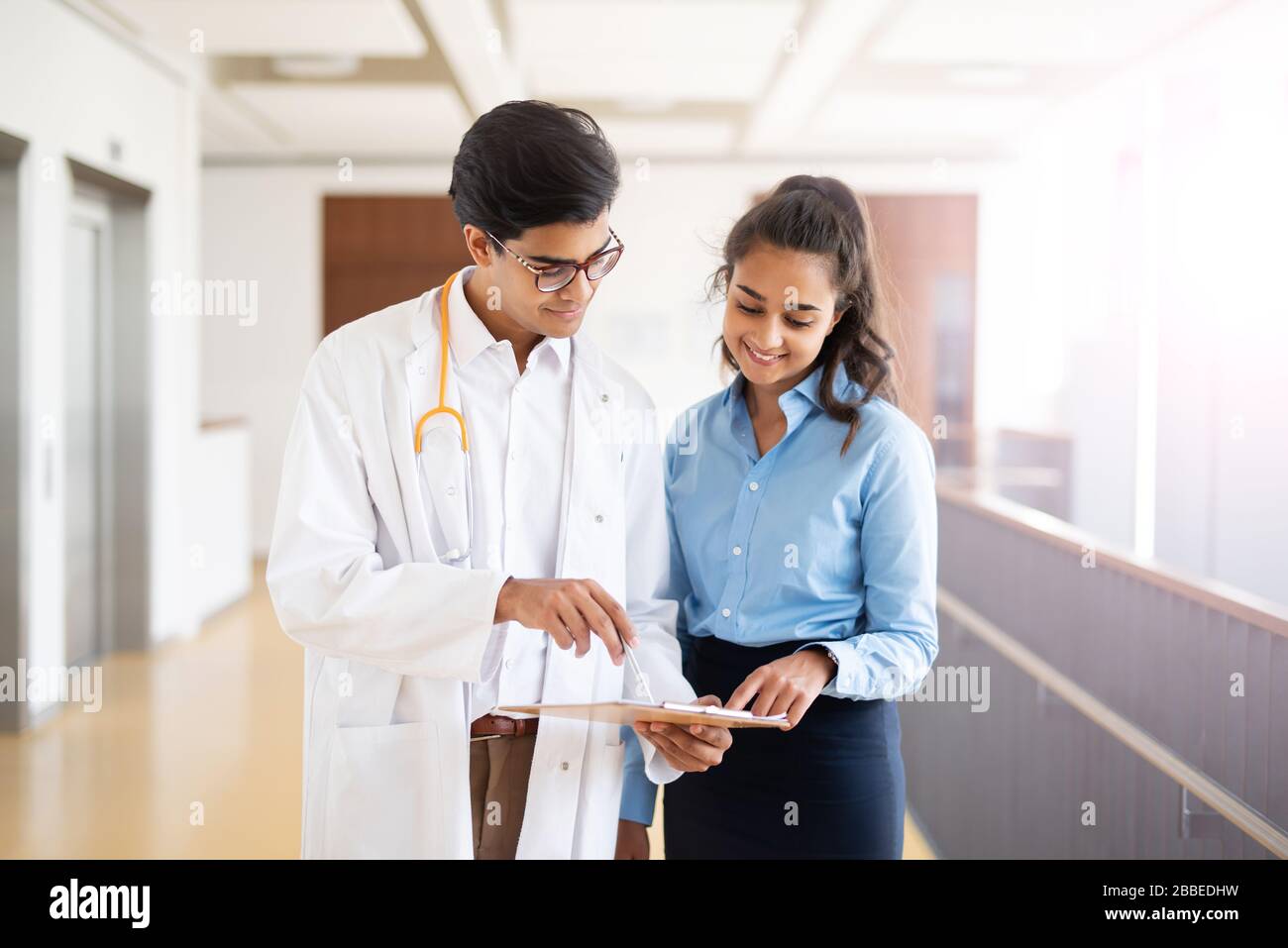 Two young doctors are discussing something in the hallway in a hospital Stock Photo