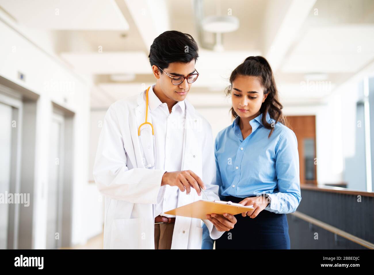 Two young doctors are discussing something in the hallway in a hospital Stock Photo