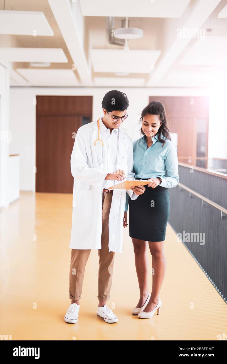 Two young doctors are discussing something in the hallway in a hospital Stock Photo