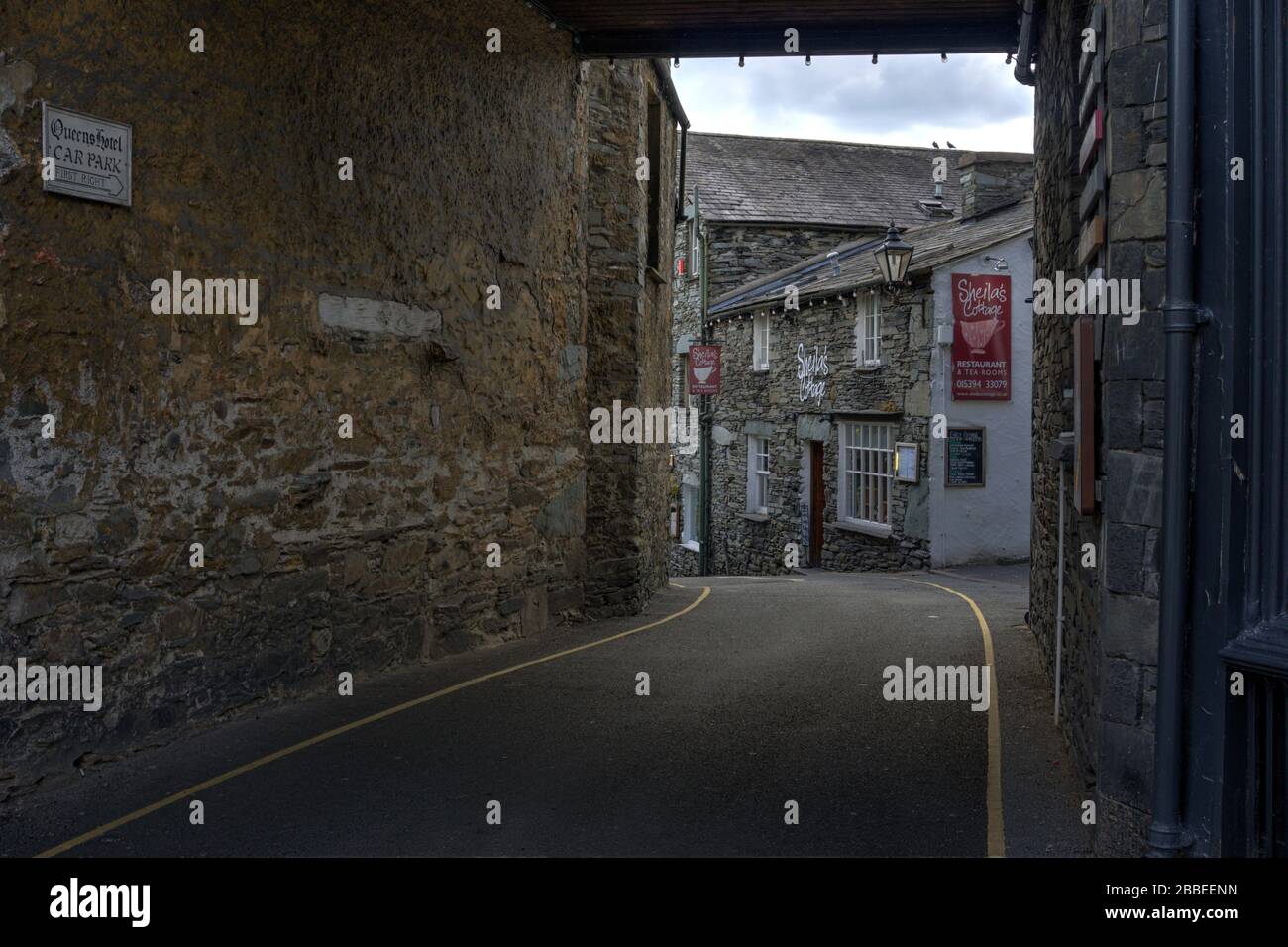Ambleside, Cumbria, United Kingdom - May 16, 2019: Exterior of Sheila's Cottage and Tea Rooms viewed along alleyway shoing road and stone built wall Stock Photo