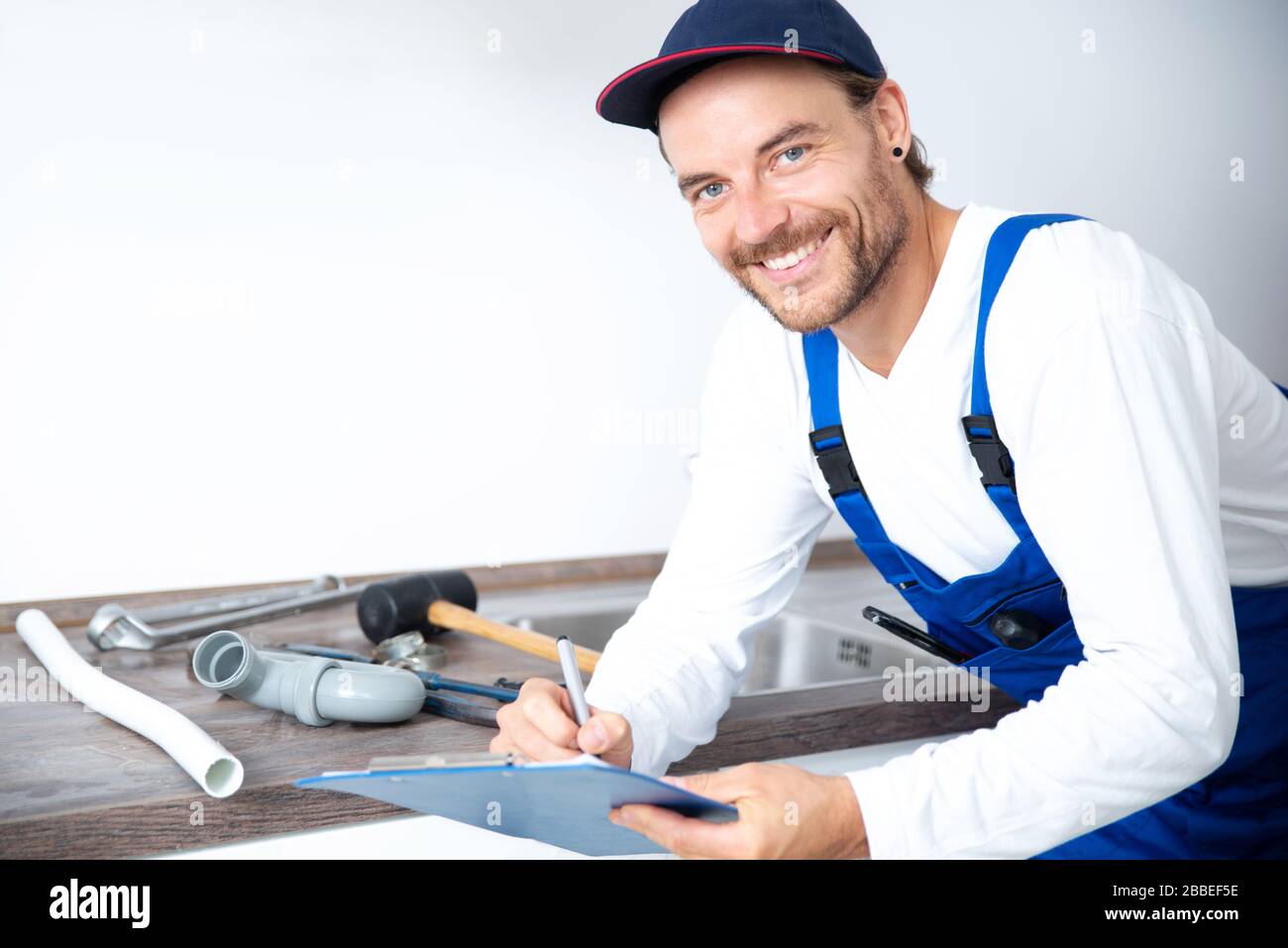 An installer works on a sink in an apartment Stock Photo