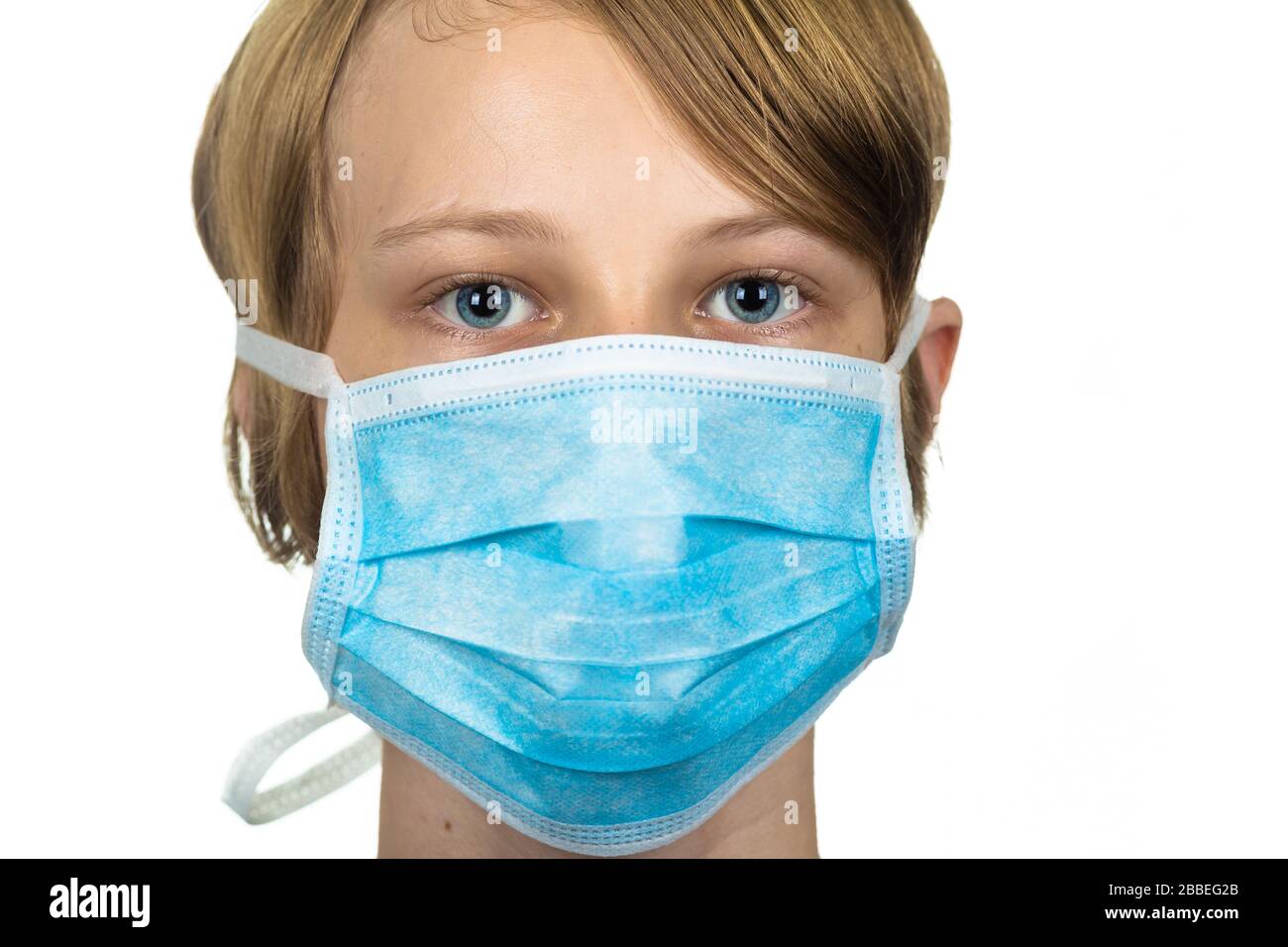 Young teenage boy wearing a protective mask to protect against virus infection.  Isolated on white. Stock Photo
