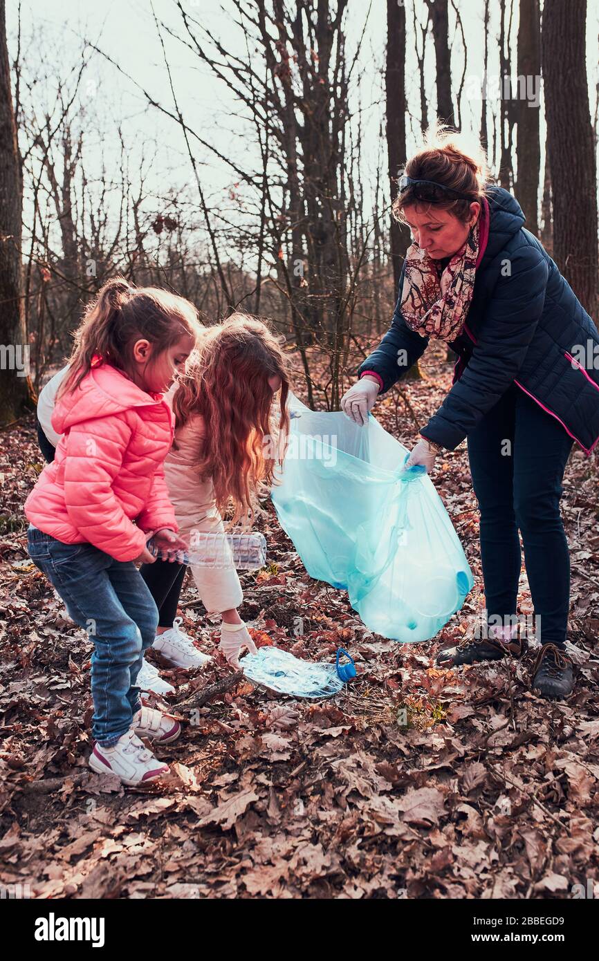 Family cleaning up a forest. Volunteers picking plastic waste to bags. Concept of plastic pollution and too many plastic waste. Environmental issue. E Stock Photo
