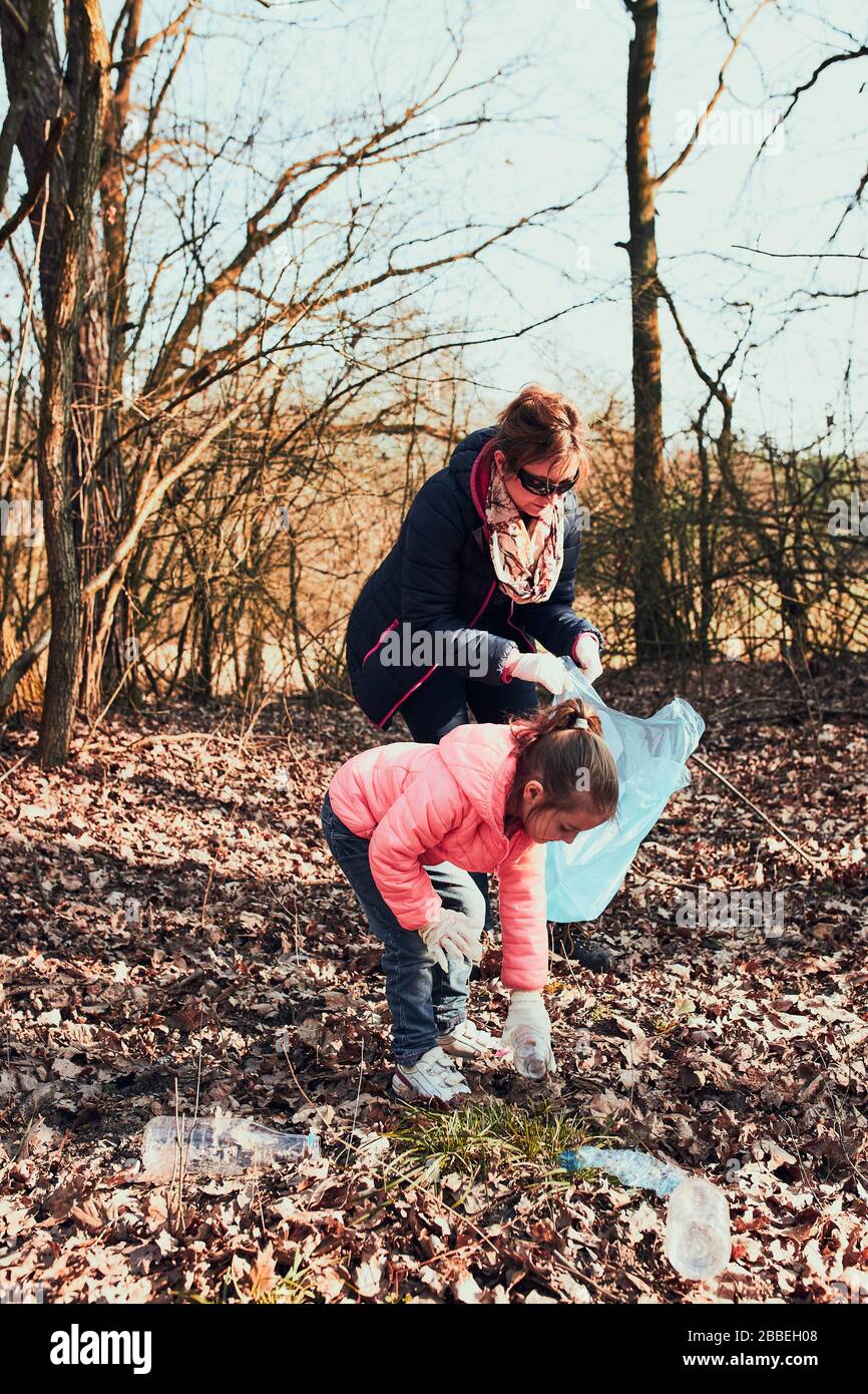 Family cleaning up a forest. Volunteers picking plastic waste to bags. Concept of plastic pollution and too many plastic waste. Environmental issue. E Stock Photo