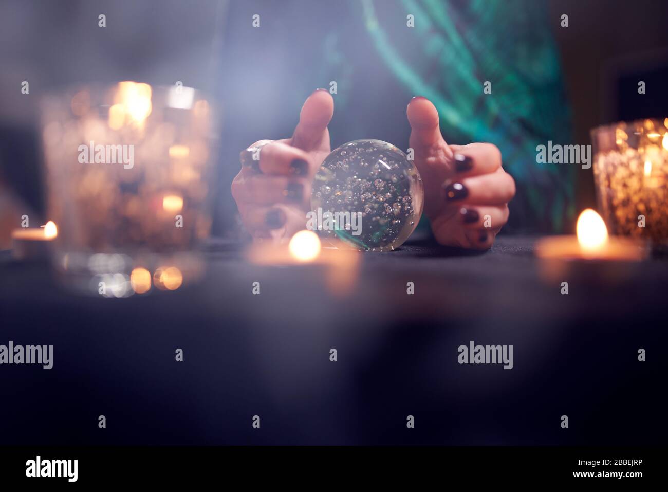 Close-up of fortuneteller woman's hands with predictions ball in dark room Stock Photo