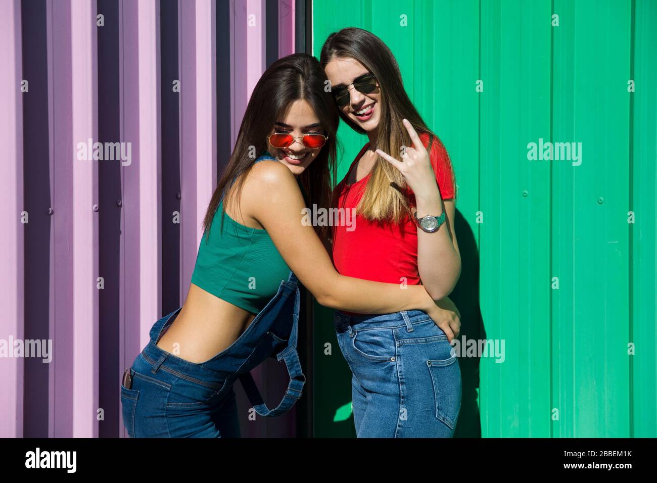 Two trendy young best female standing by the wall on a hot summer day Stock Photo