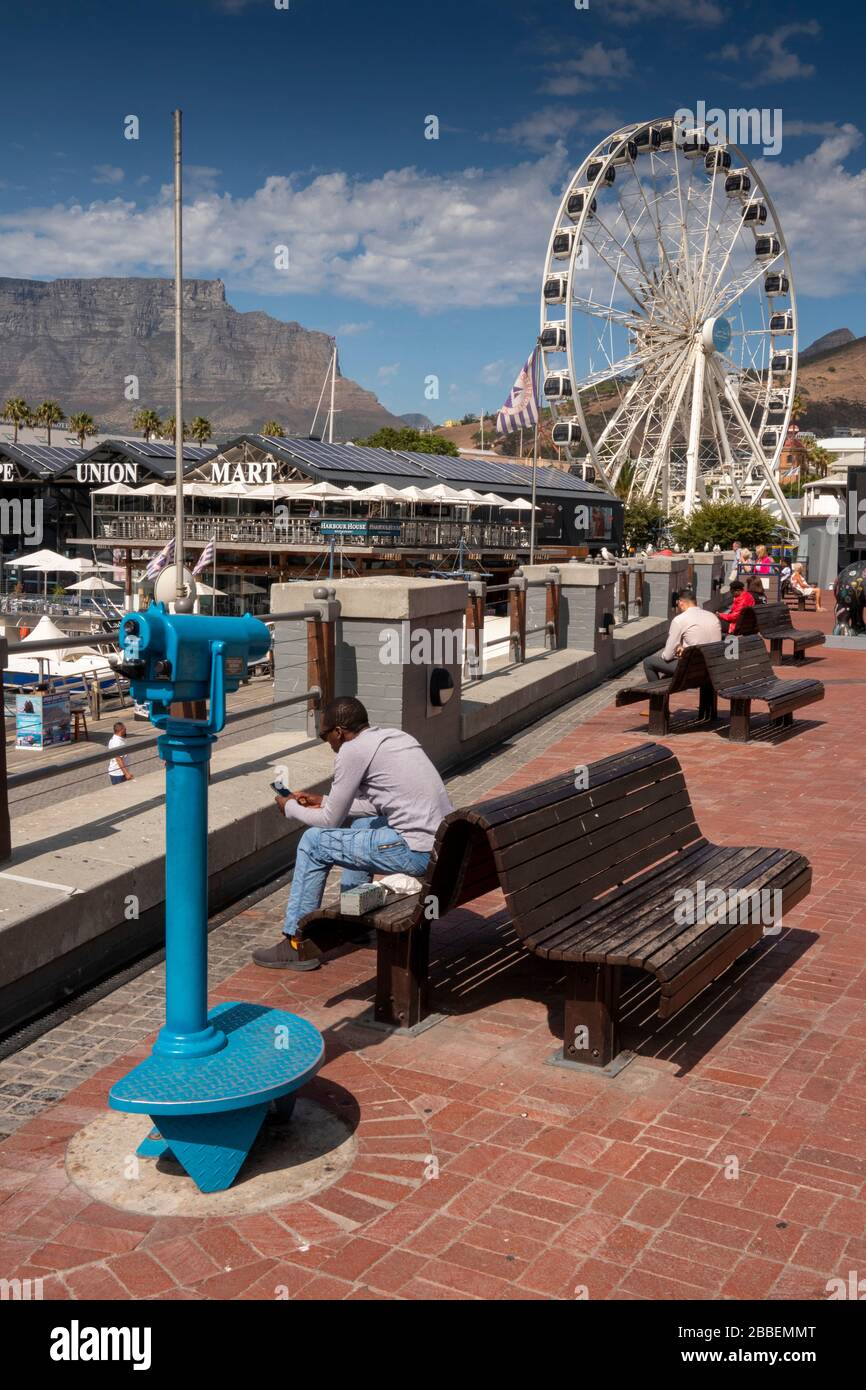 South Africa, Western Cape, Cape Town, Victoria and Alfred Waterfront, visitors sat in sunshine at waterside seating Stock Photo