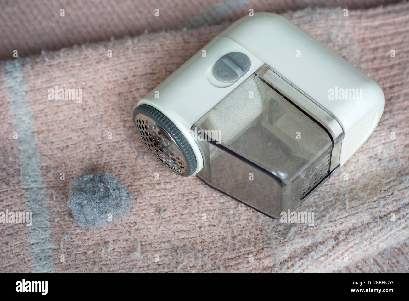 Pilled sweater. Handheld electric fabric shaver fuzz remover device machine for removing fuzz, lint and pills on clothes. Stock Photo