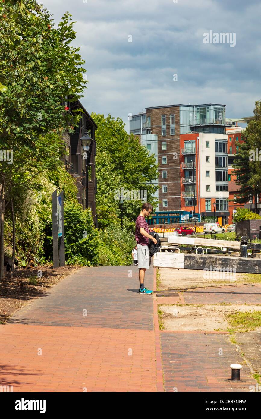 A man stands and searches his bag on the Towpath of the Birmingham and