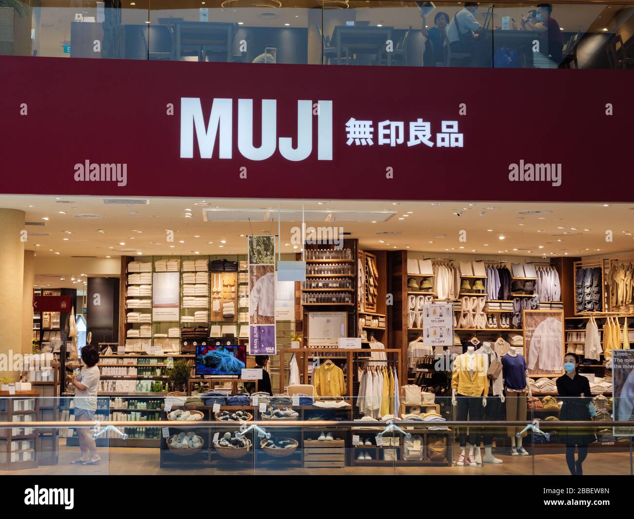 SINGAPORE – 23 MAR 2020 – Frontage of an almost empty MUJI retail store in Jewel Mall, Changi Airport, Singapore. An Asian lady wearing a mask stands Stock Photo