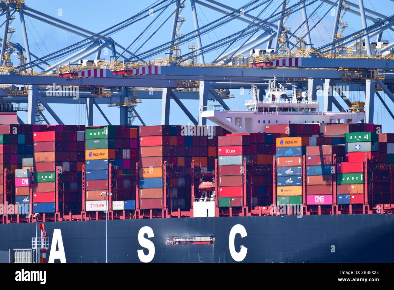 Rotterdam, The Netherlands - August 2019; Close up view of mid-section of container ship,  handling ‘ship to shore’ in the terminal with gantry cranes Stock Photo