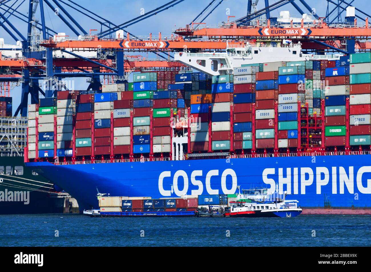 ow angle view of container ship, ‘ship to shore’ in the terminal; gantry cranes rising high above the ship and Stock Photo