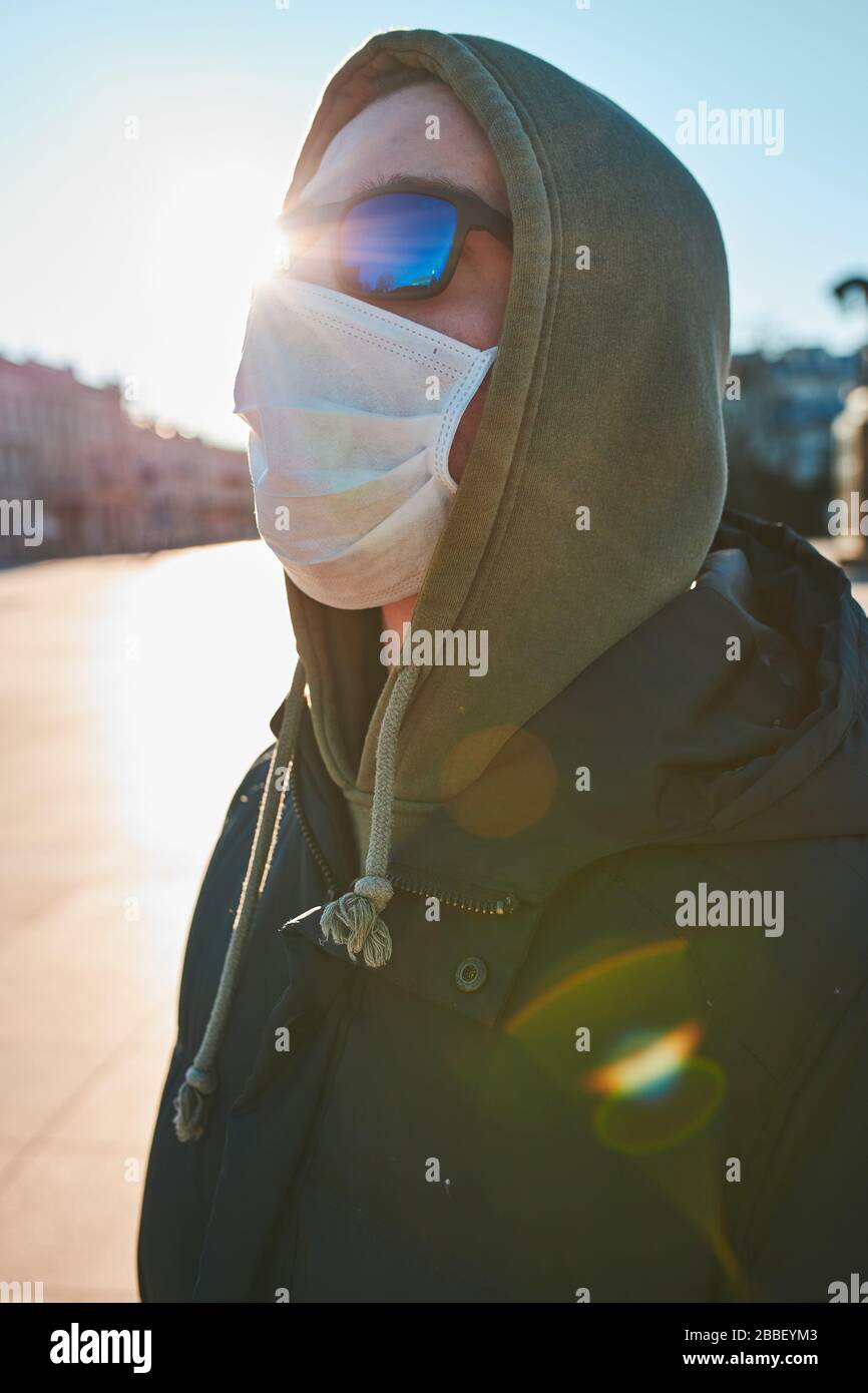 Young man in the hood wearing the face mask to avoid virus infection