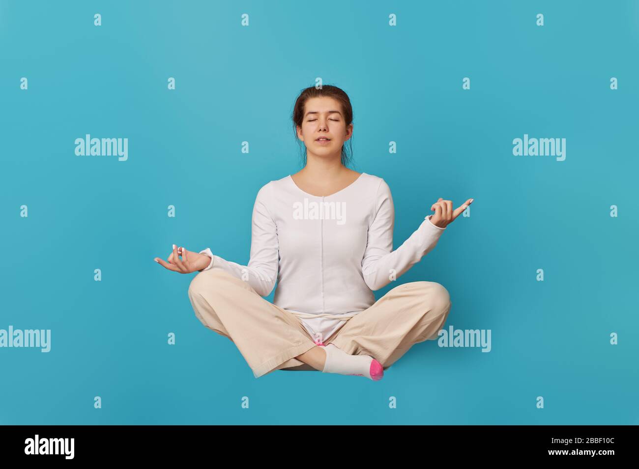 Woman levitates and relaxing in lotus pose. Concept of mental helth, psychological and emotional well-being in quarantine time. Stock Photo