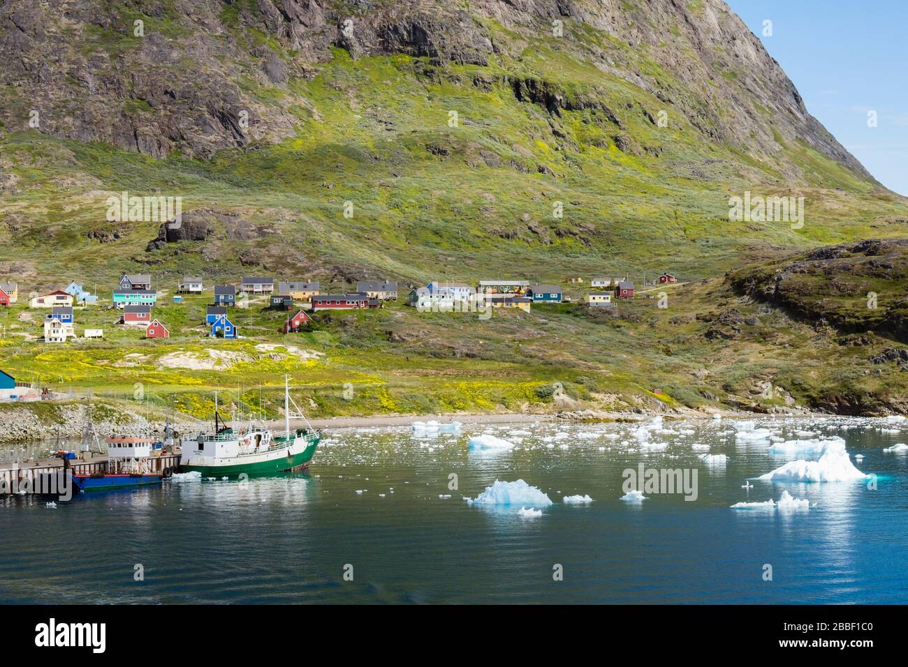 Offshore view to port below Qaqqarsuaq Fjeld mountain with traditional houses overlooking icebergs from Tunulliarfik Fjord. Narsaq Kujalleq Greenland Stock Photo