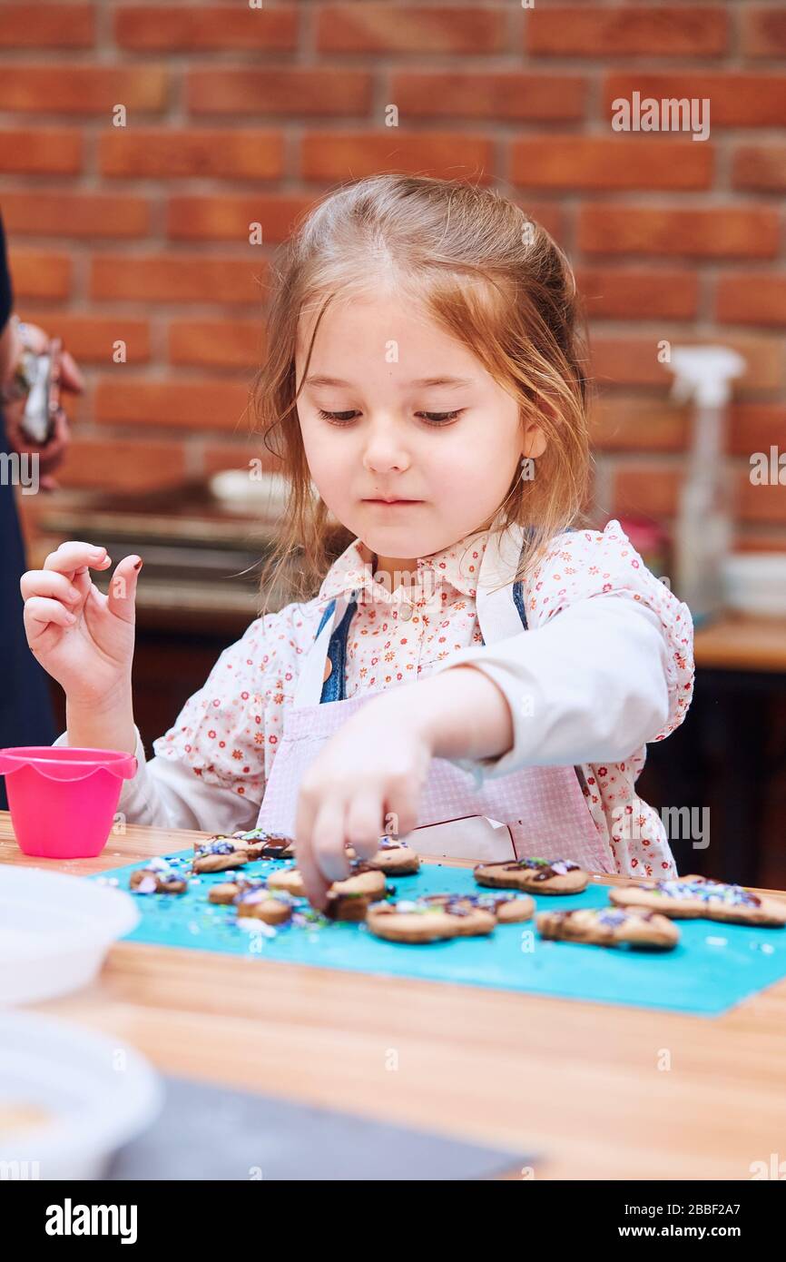 Little Girl Decorating Her Baked Cookies With Colorful Sprinkle