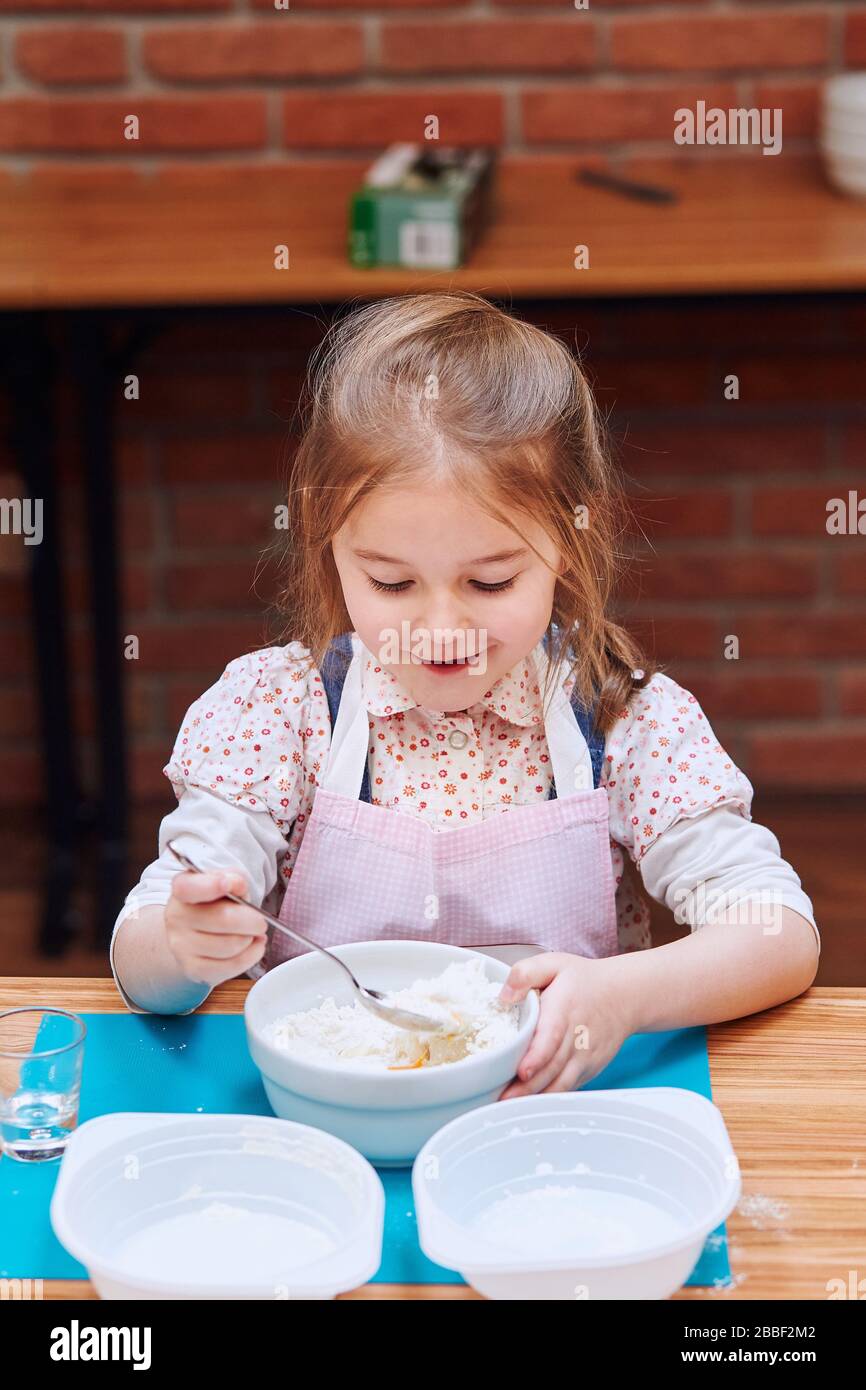 Little girl combining the ingredients for baking the cake. Kid taking